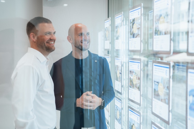 Zwei Geschäftspartner betrachten lachend ihr Schaufenster