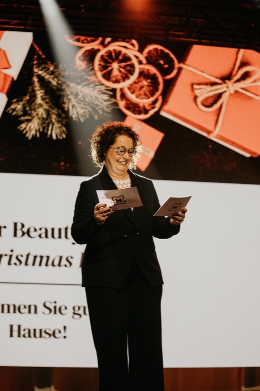 Rednerin liest am Pult vor einer weihnachtlich gestalteten Leinwand